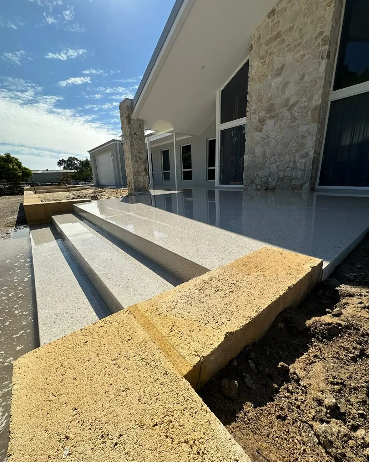 Honed concrete steps and entry landing at the front of a stone clad house