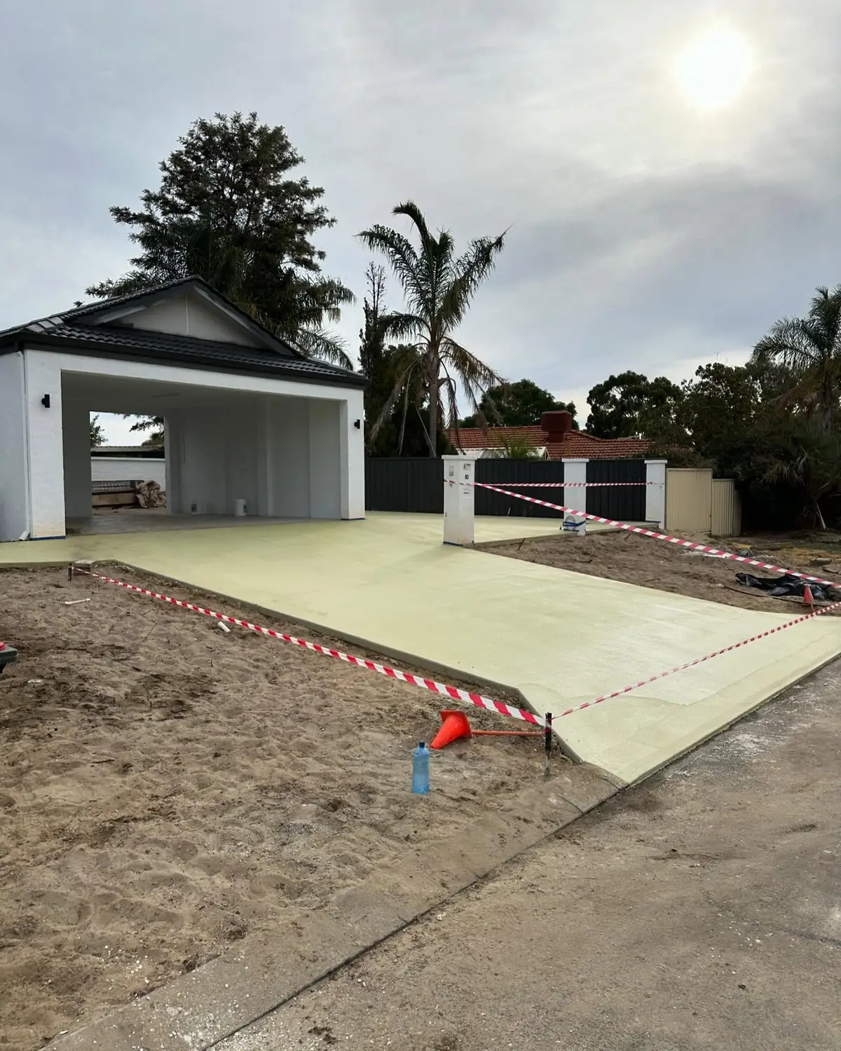 Freshly poured driveway slab in front of a garage, taped off and curing