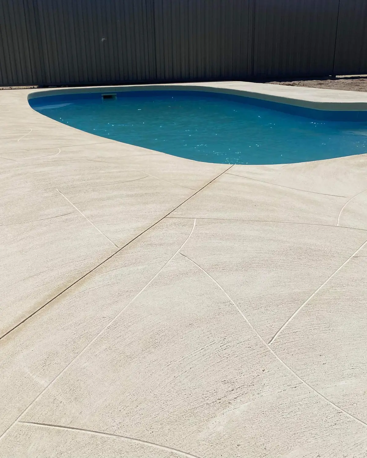 Liquid limestone pool surround cut into panels around a kidney shaped pool