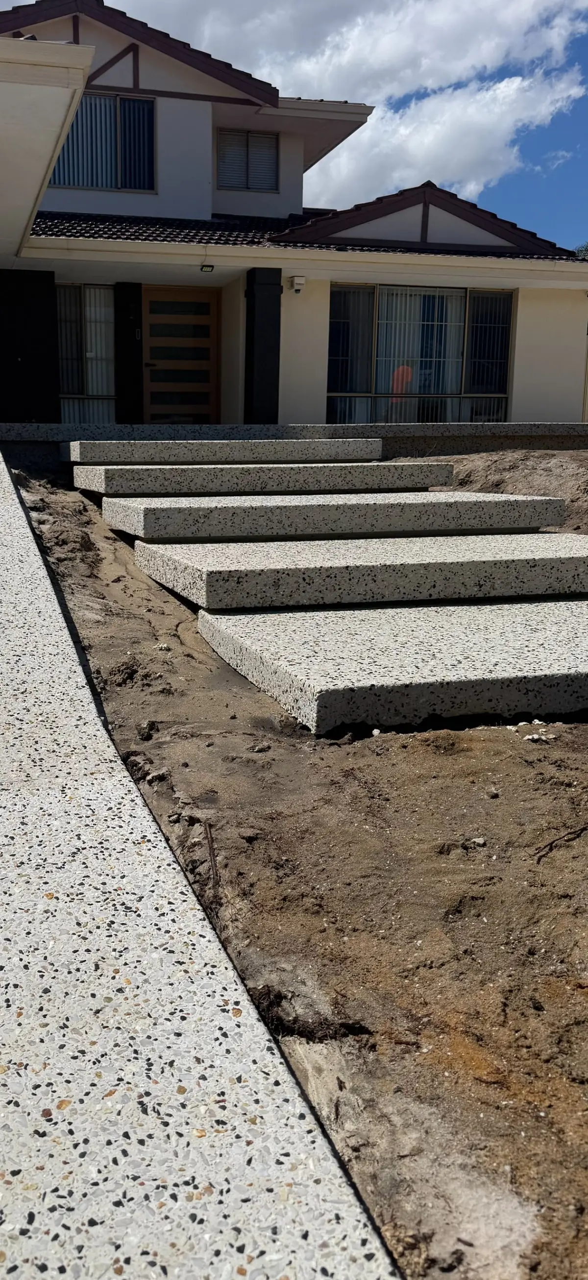 Floating exposed aggregate steps leading up to the front of a house